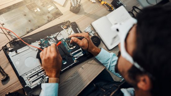 Hardware, engineering and IT professional repair motherboard, microcircuit or electronic device in a workshop or shop. Overhead, man and guy fixing a computer for technology in a lab or factory.